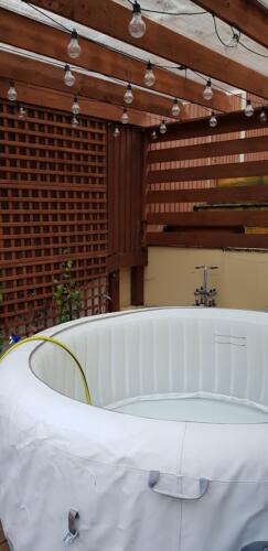 Hot tub under and wooden pergola, with lantern lights
